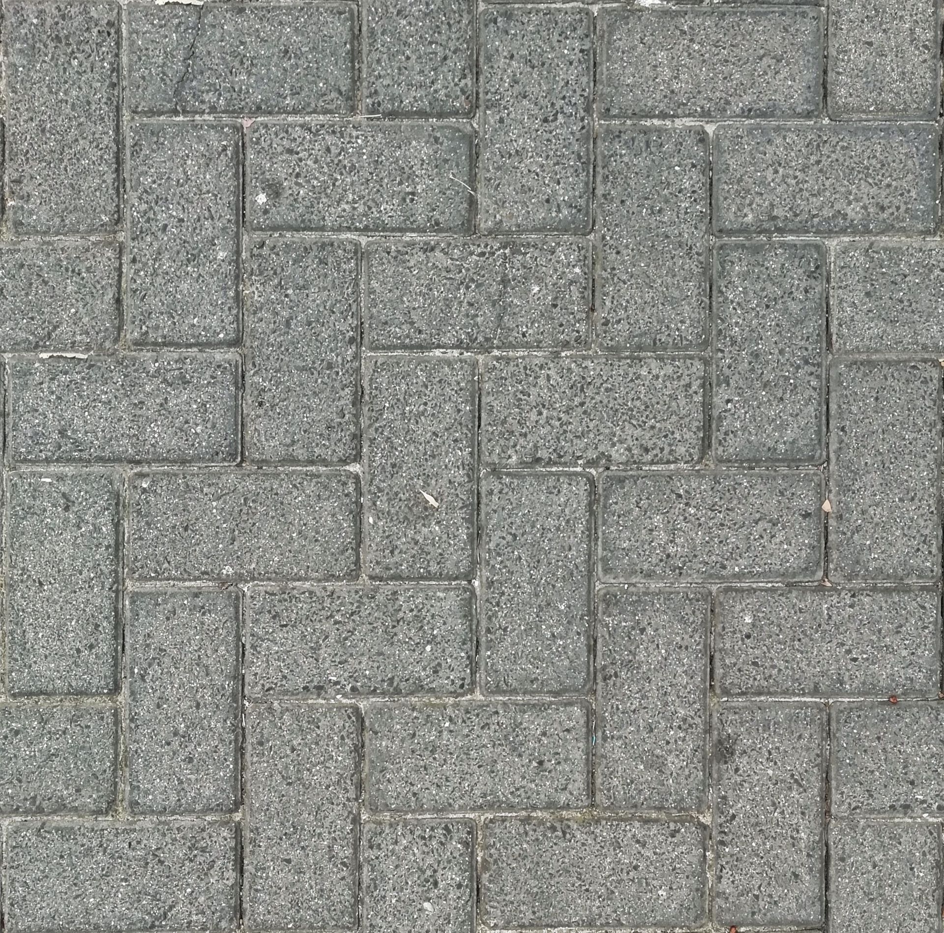 A herringbone pattern made of gray stone pavers photographed from above, offering a textured surface view.